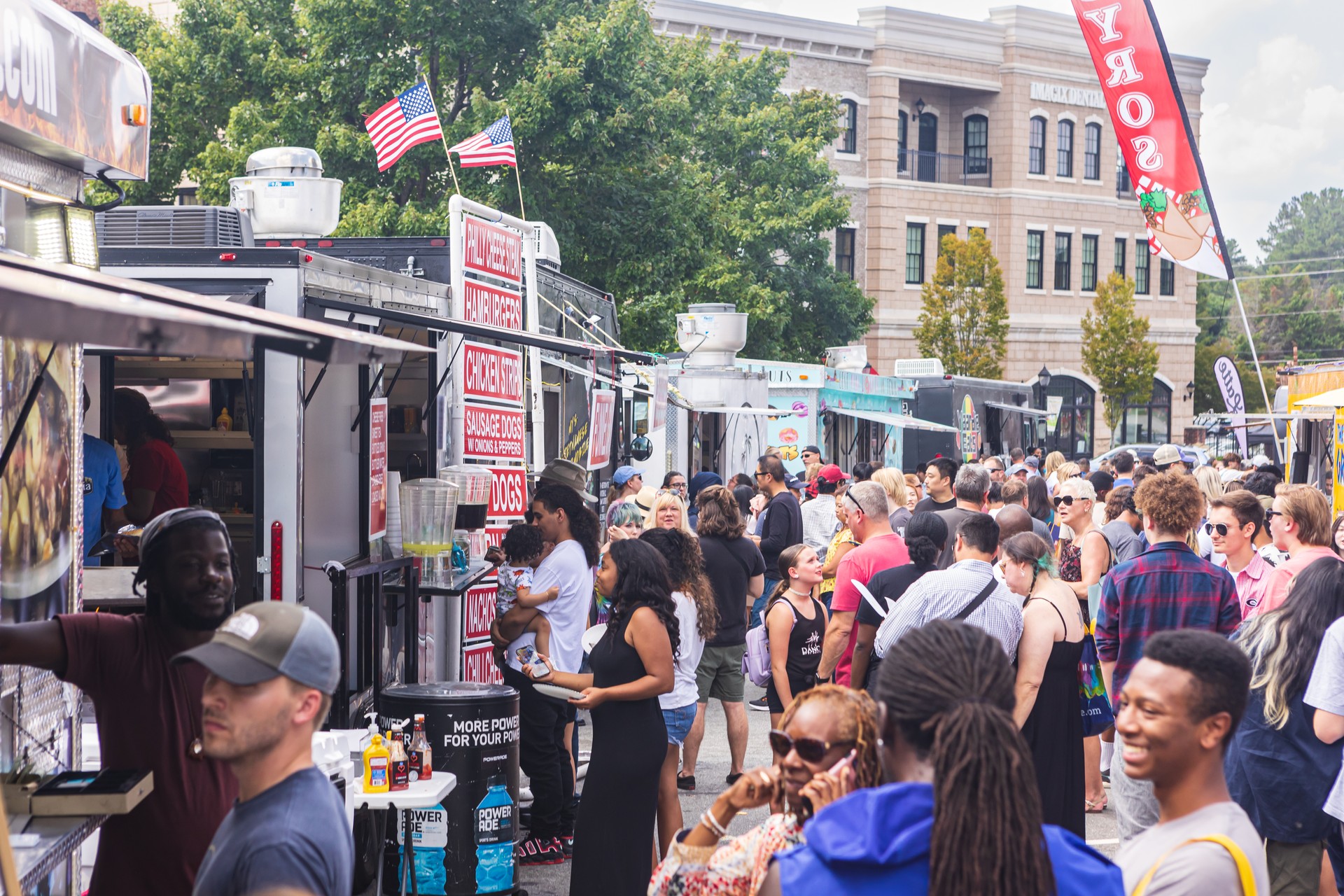 Large crowd of people wait in line at food trucks